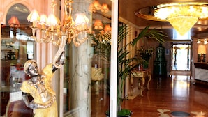 Un hall d’entrée agrémenté d’une colonne en marbre, d’un lustre et d’un comptoir d’accueil.