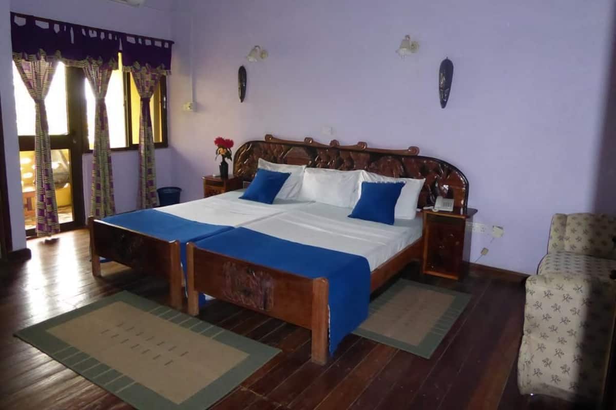 A bedroom with a wooden bed, a nightstand, a chair, and a window with curtains.