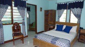 Un dormitorio con una cama, una silla, un armario y un espejo.