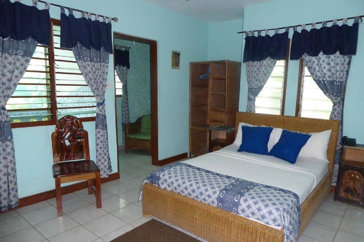 A bedroom with a bed, a chair, a wardrobe, and a mirror.