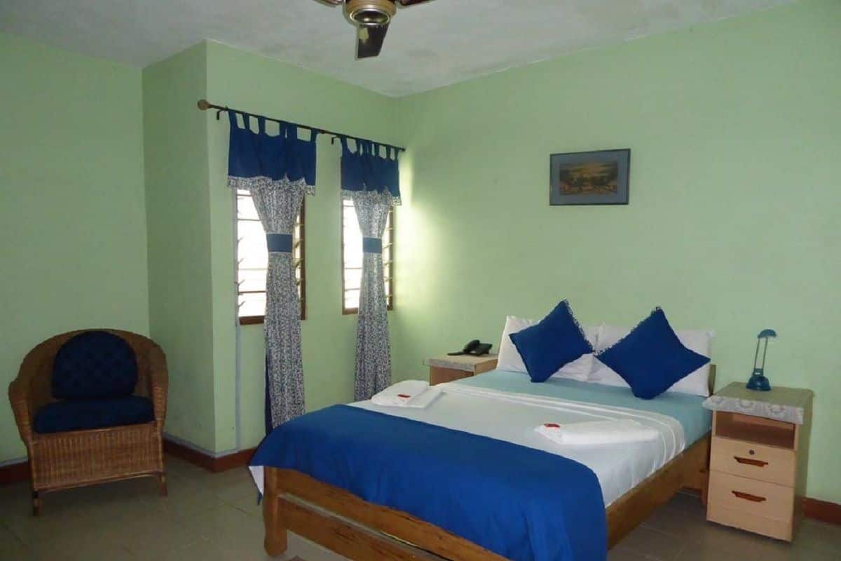 A bedroom with a bed, a chair, a nightstand, and a ceiling fan.