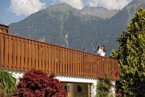 A wooden balcony overlooking a mountainous landscape. - Olympic Royal (Giustino)