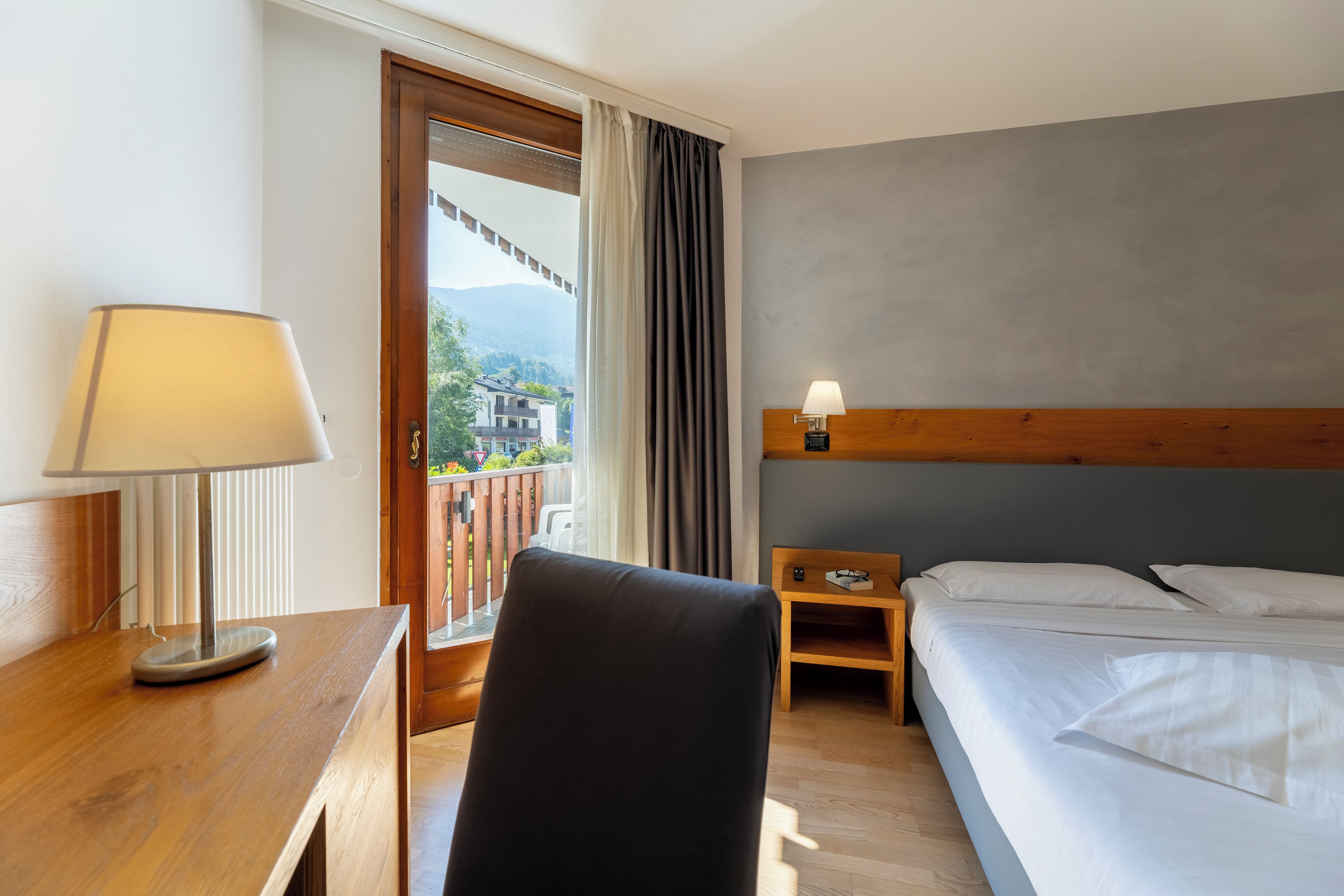 Une chambre d’hôtel avec un lit, un bureau doté d’une lampe, une chaise et une vue sur l’extérieur.