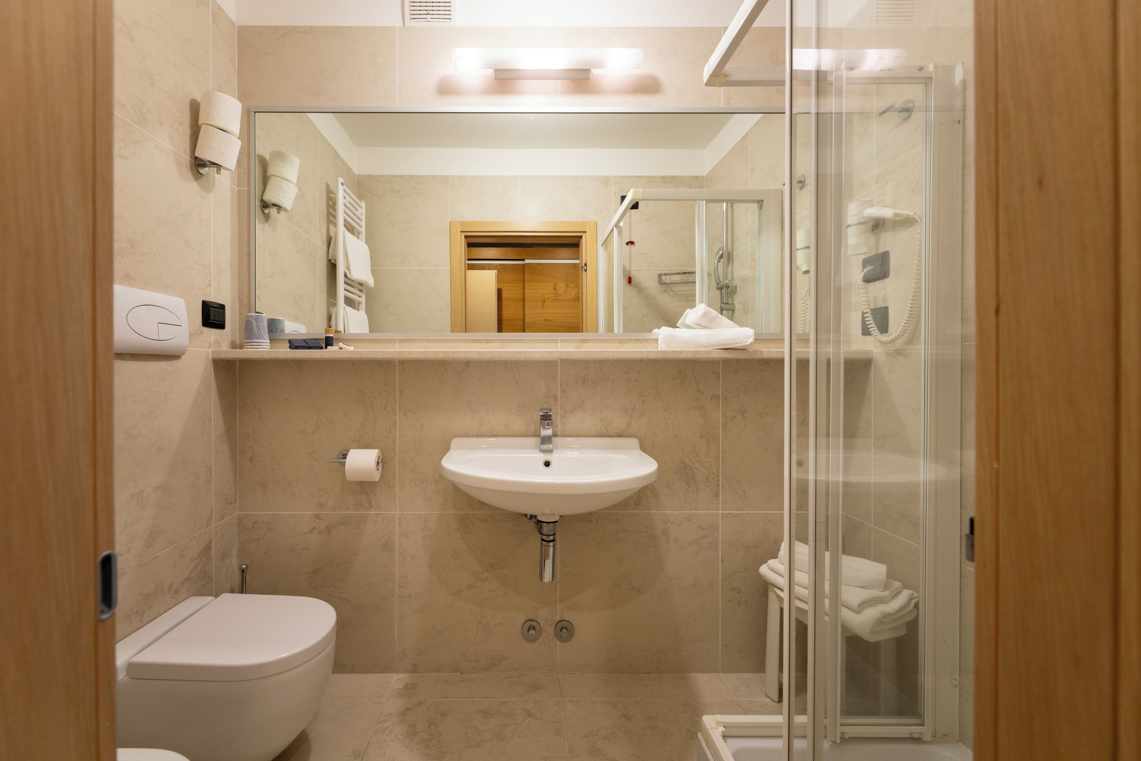 Un baño moderno con inodoro, lavamanos y ducha con cerramiento de vidrio.