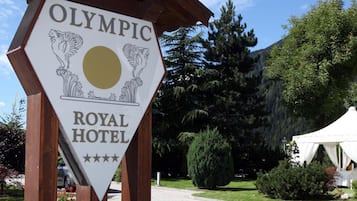 A sign for the Olympic Royal Hotel with a logo featuring two winged horses and a sun.
