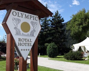 A sign for the Olympic Royal Hotel with a logo featuring two winged horses and a sun.