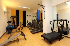 A gym with various exercise equipment including treadmills, weight machines, and a punching bag.