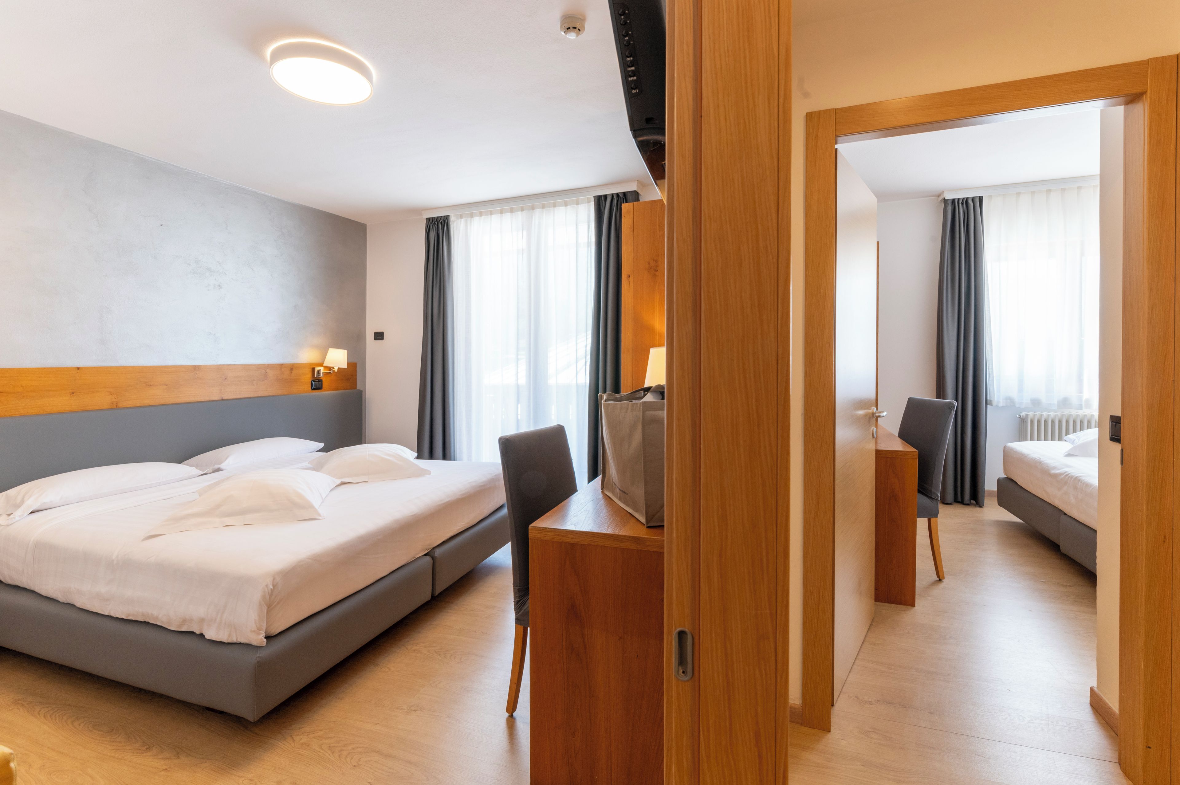 Ein Hotelzimmer mit einem Bett, einem Schreibtisch, einem Stuhl, einem Spiegel und einem Kleiderschrank.