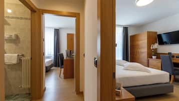 A hotel room with a bed, a desk, a television, and a bathroom with a shower and toilet.