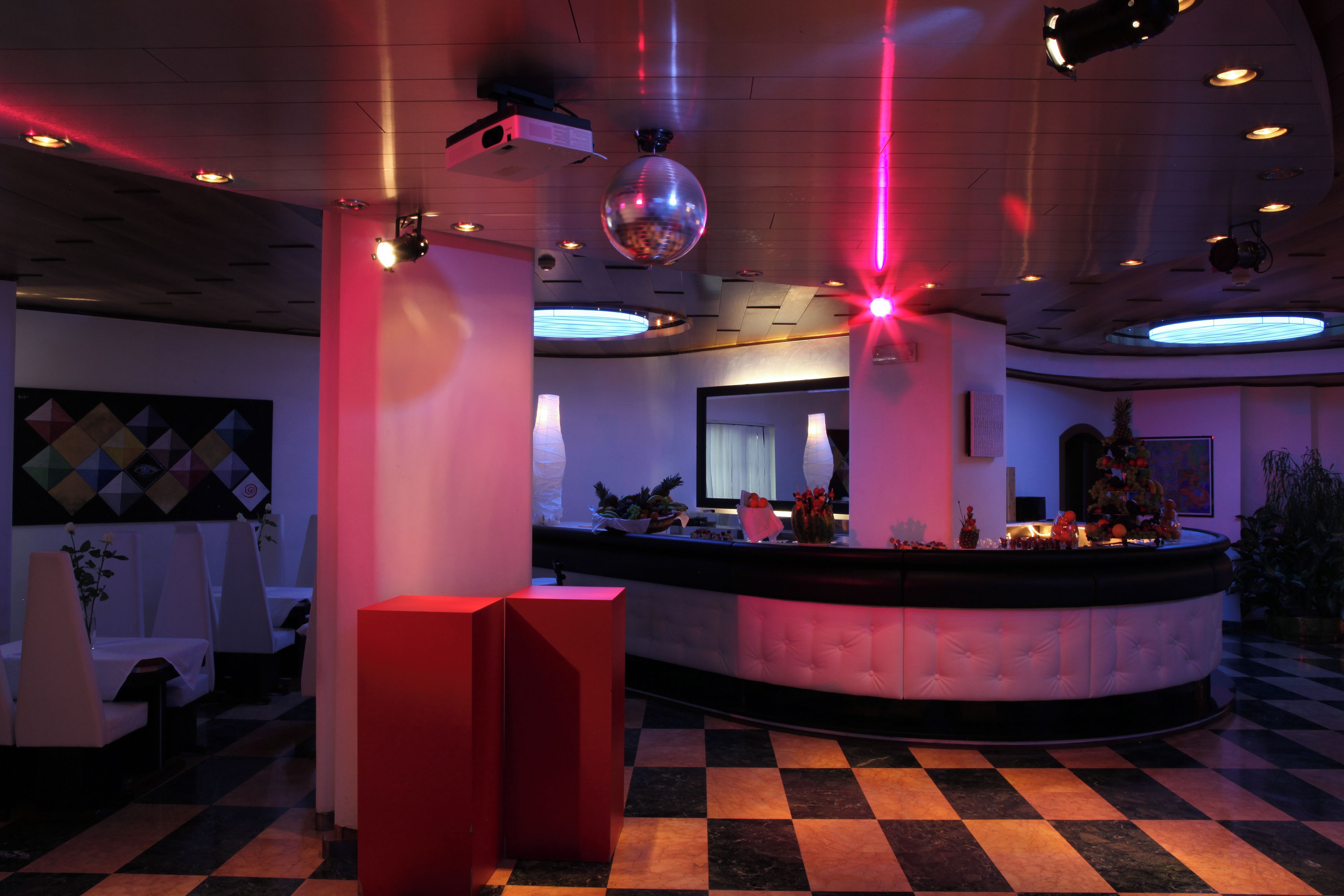 Un vestíbulo con piso a cuadros, una recepción y una gran bola de discoteca.