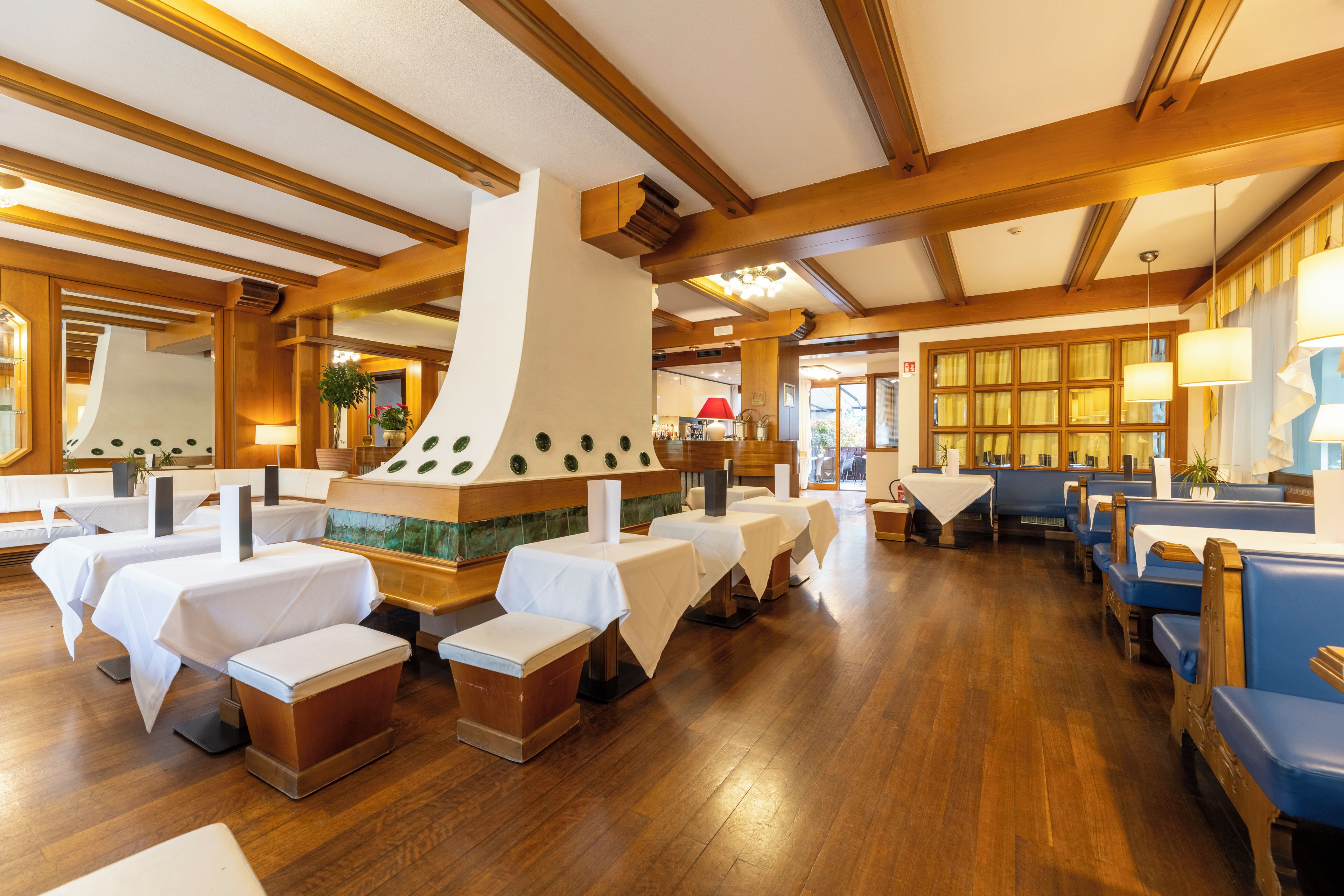 A restaurant with wooden beams, white tables, and blue booths.