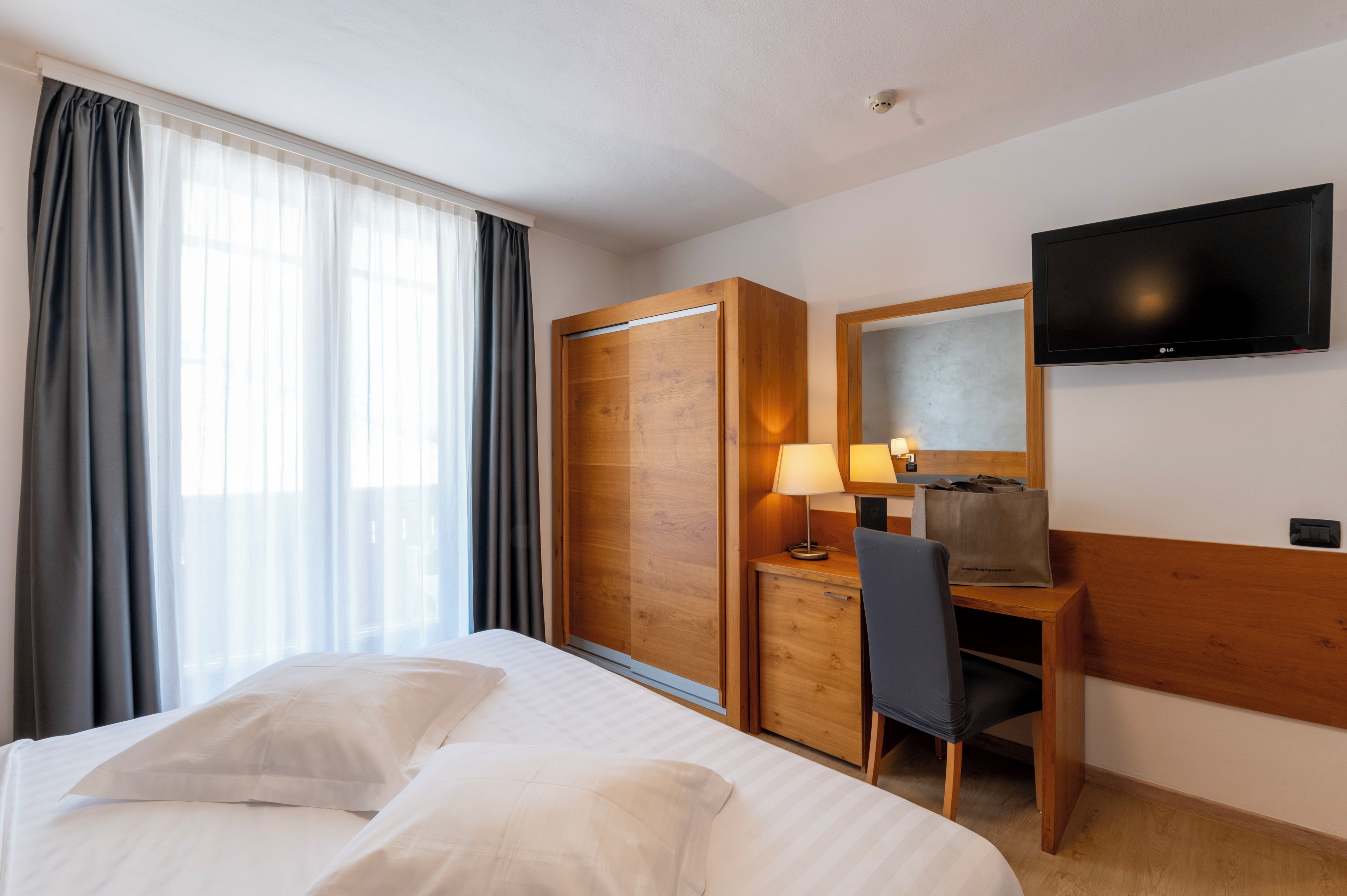 Ein Hotelzimmer mit einem Bett, einem Schreibtisch, einem Sessel, einem Fernseher und einem Kleiderschrank.