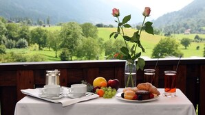 A breakfast table with a tray, a cup, a glass of juice, a plate of pastries, and a vase with flowers. - Olympic Royal (Giustino)