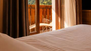 Una habitación de hotel con cama, cortinas y vistas a un balcón con una silla.