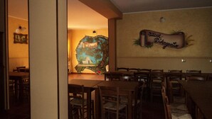 Interior de un restaurante con mesas y sillas de madera, un mural en la pared y un letrero que dice 'Mister Despensas'.