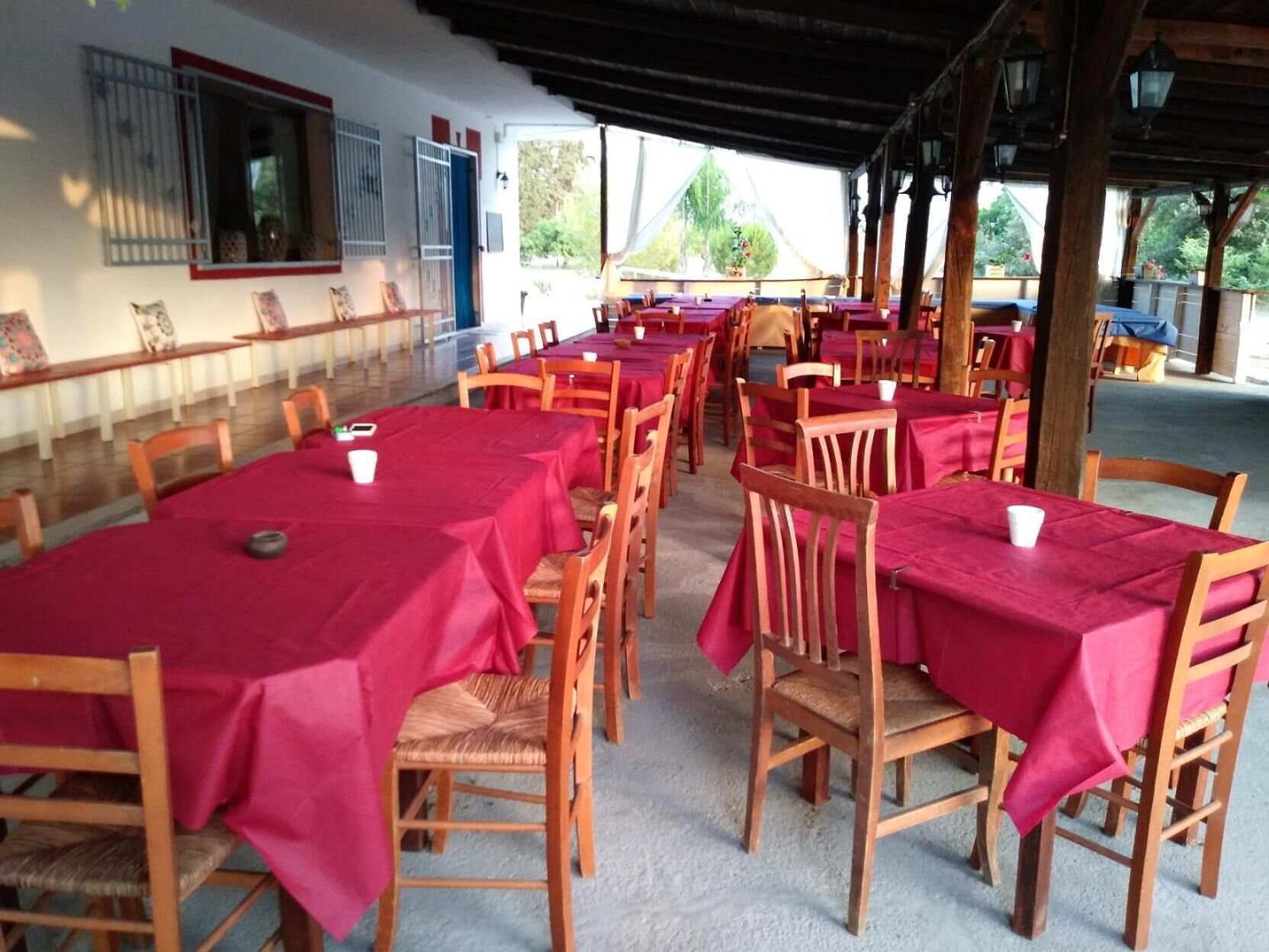 A covered outdoor dining area with multiple tables and chairs, arranged in rows.