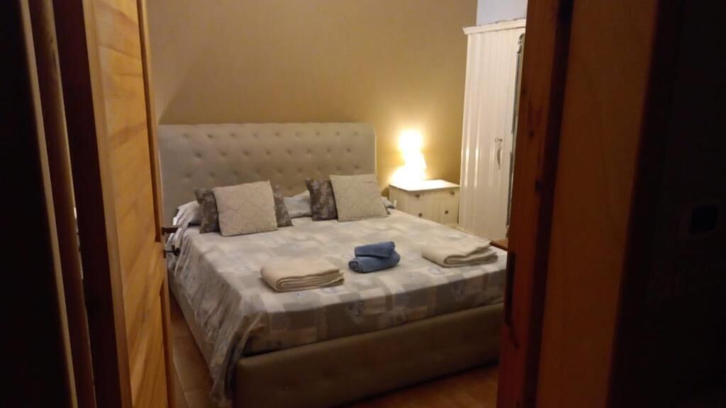 Une chambre à coucher avec un lit, des oreillers, une table de chevet et une lampe.
