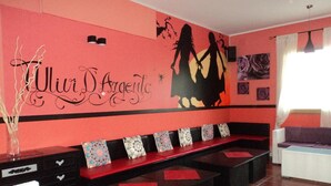 Una habitación con pared roja, un banco con cojines estampados y una pared decorativa con siluetas y texto.