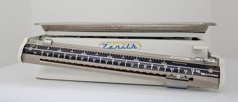 A vintage Zenith typewriter with a ruler and weight scale.