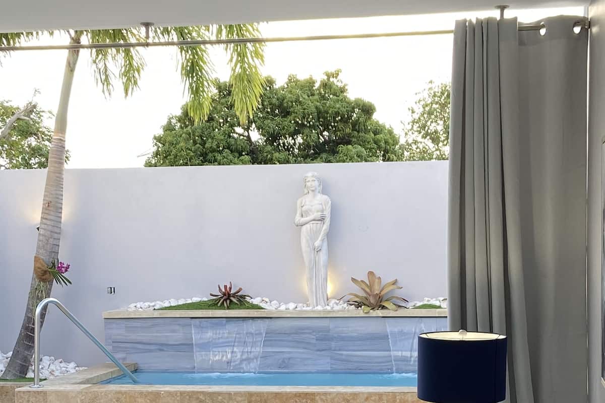 A modern outdoor seating area with a pool, a statue, and a lamp.