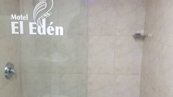 A shower area with a tiled wall and a logo for Motel El Eden.