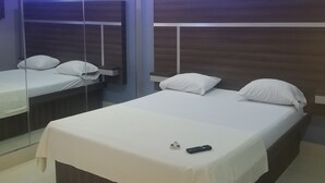 Quarto moderno com cama grande, mesa de cabeceira e espelho.
