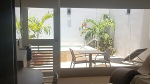 Quarto moderno com uma grande porta de vidro deslizante que dá para uma área externa. No interior, há um sofá, uma poltrona e uma mesa pequena.