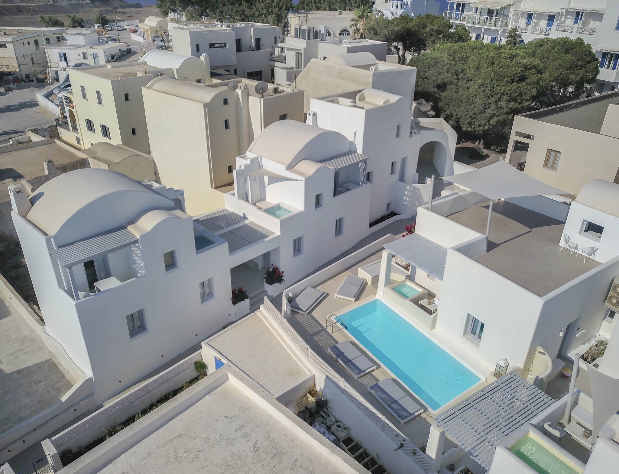 Et moderne boligområde med hvide bygninger, en swimmingpool og et lille haveanlæg.