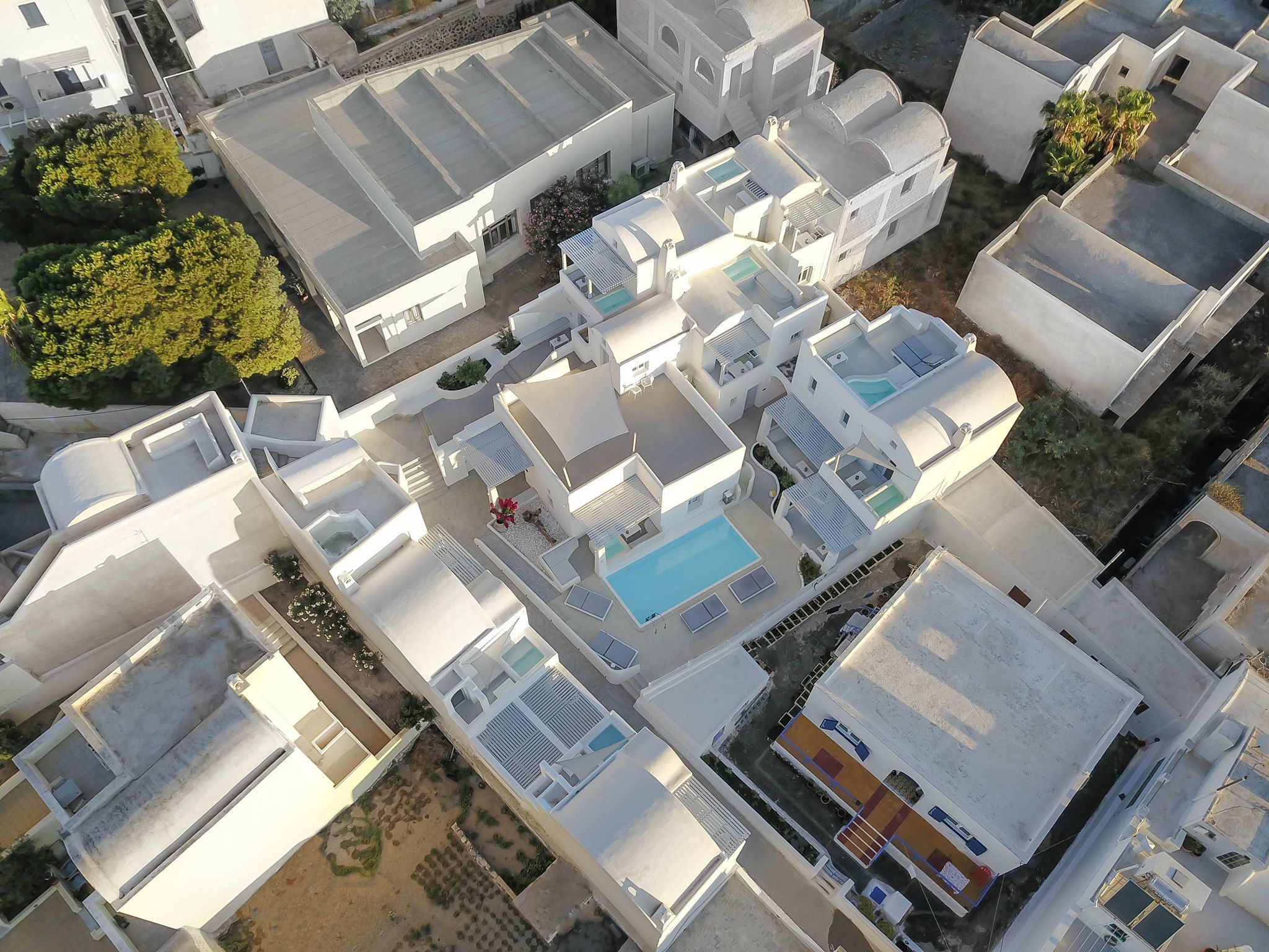 An aerial view of a residential complex with multiple buildings, a swimming pool, and a small garden area.