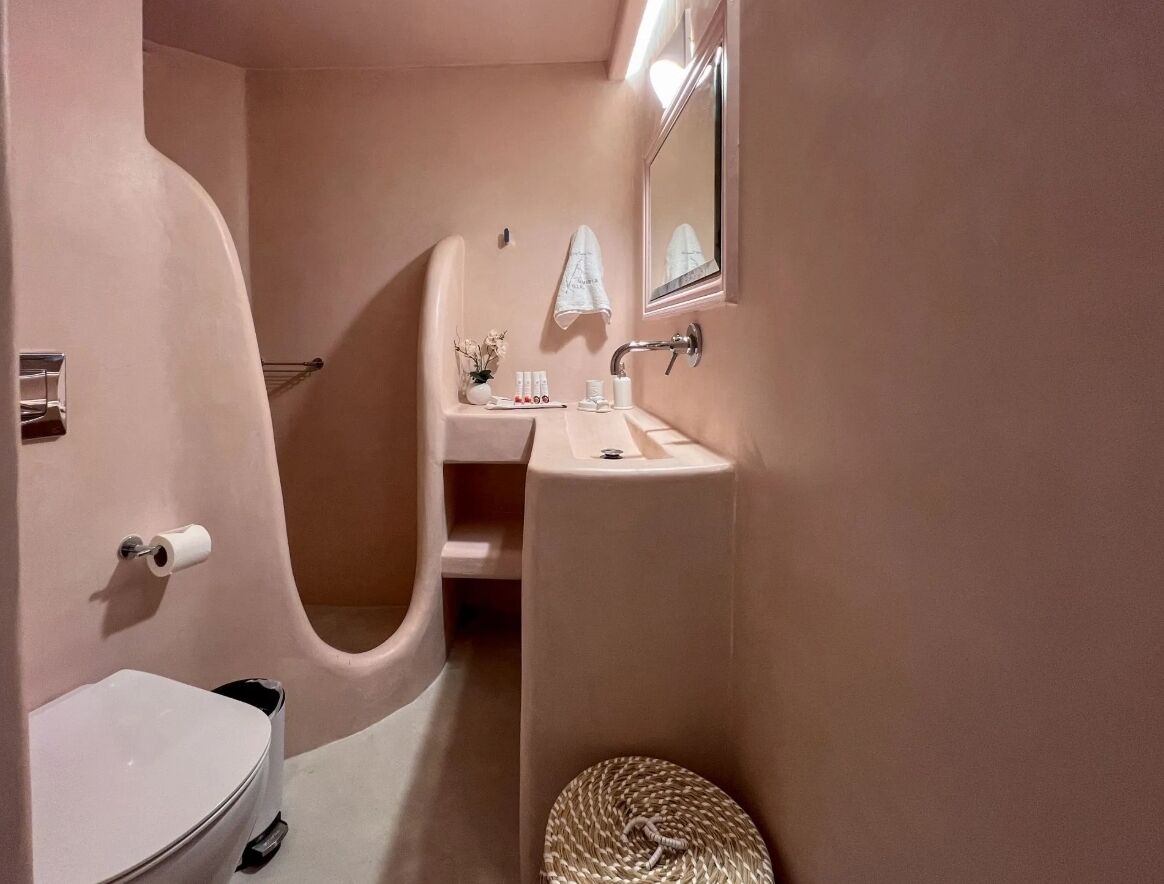 A bathroom with a white toilet, a sink, and a mirror.