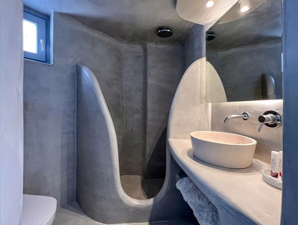 A modern bathroom with a freestanding bathtub, a round sink, and a shower area.