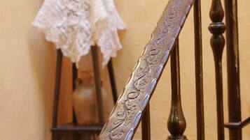 Una escalera con barandillas metálicas ornamentadas y una cesta de mimbre con frutas sobre una mesa a su lado.