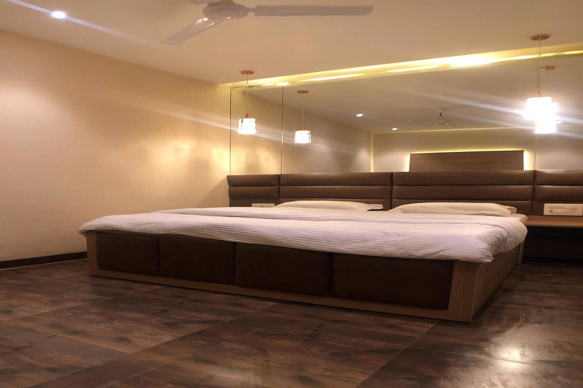 A modern bedroom with a large bed, wooden headboard, and a ceiling fan.