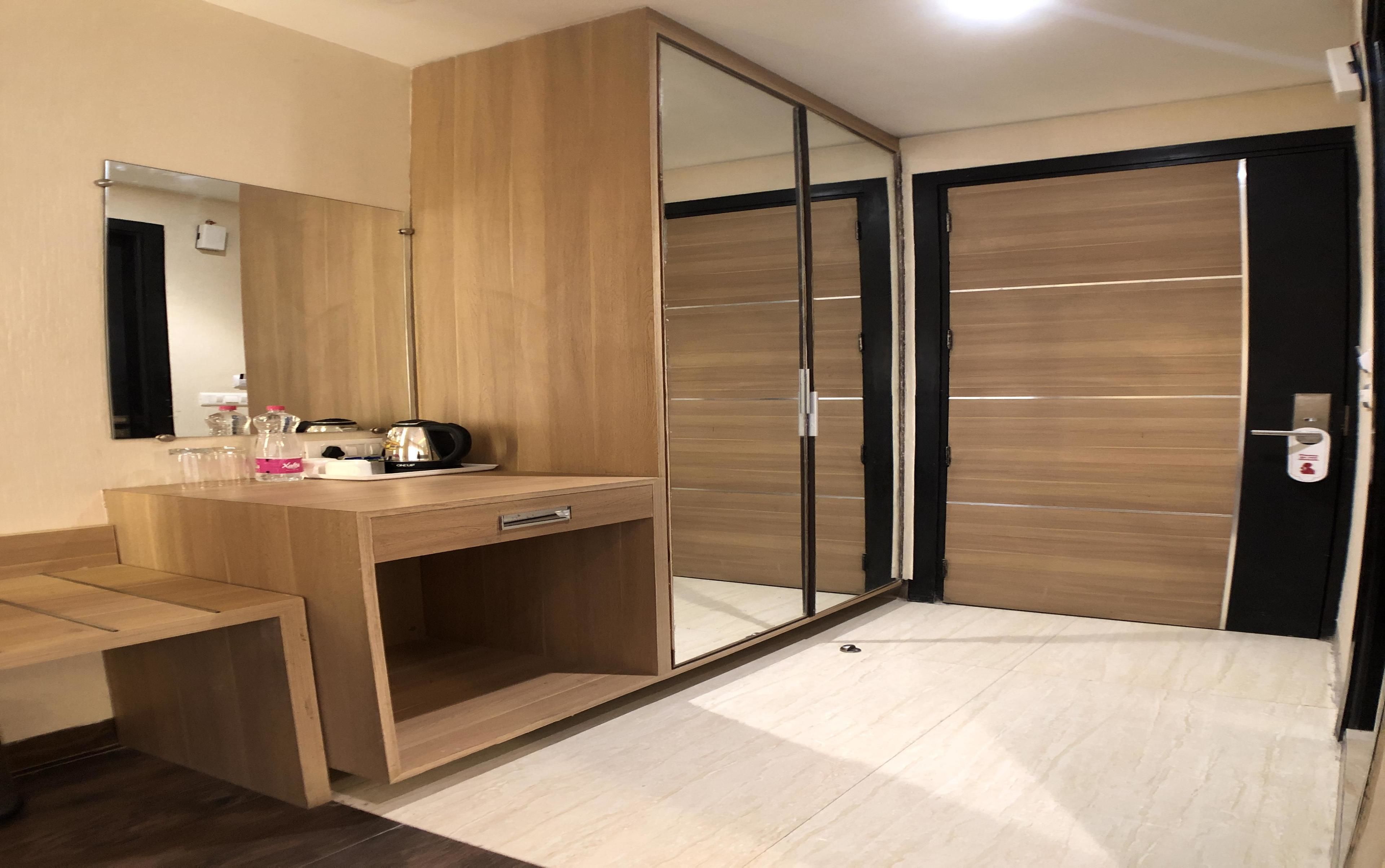 Ein modernes Schlafzimmer mit Schminktisch aus Holz, einem großen Spiegel, einem Kleiderschrank mit Schiebetüren und einem Nachttisch.