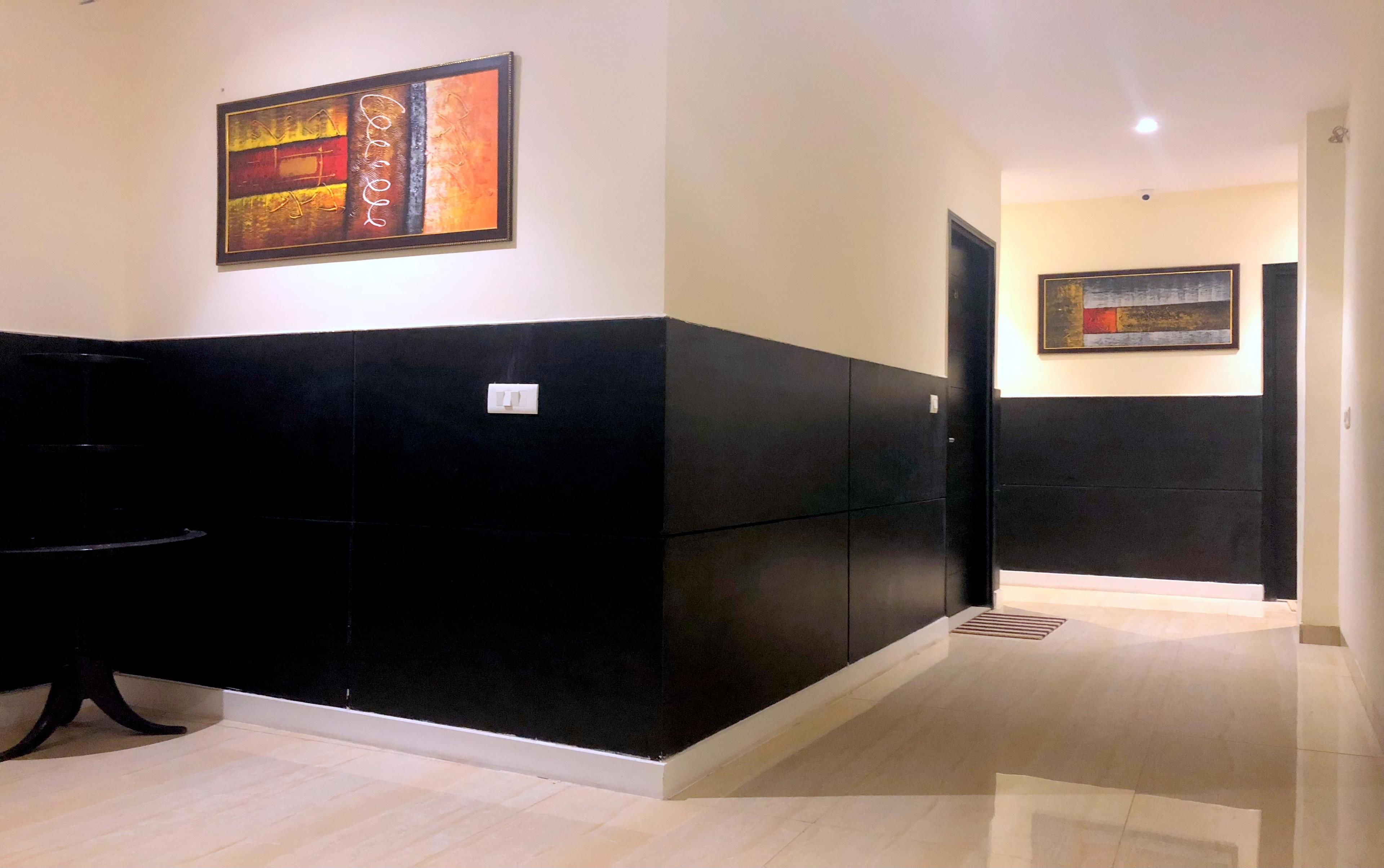 A hallway with black and white walls, a tiled floor, and two framed artworks on the walls.