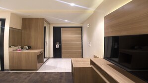 A modern hotel room with a wooden wardrobe, a built-in TV, and a small kitchenette area. - Solitaire Hotel (New Delhi)