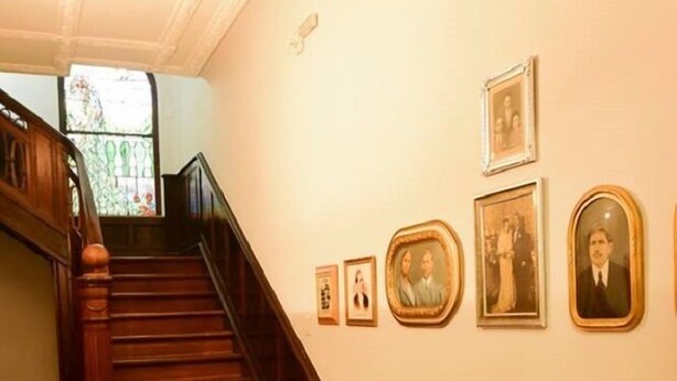 A staircase with wooden railings, a patterned floor, and a sofa with a cushion. - Hotel Praça da Matriz (Porto Alegre)
