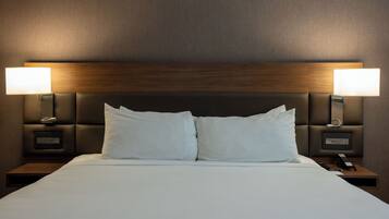 A hotel room with a large bed, two bedside lamps, and a wooden headboard.