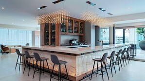 Un espace bar moderne doté d’un comptoir en marbre, de plusieurs tabourets et d’un meuble à vin.