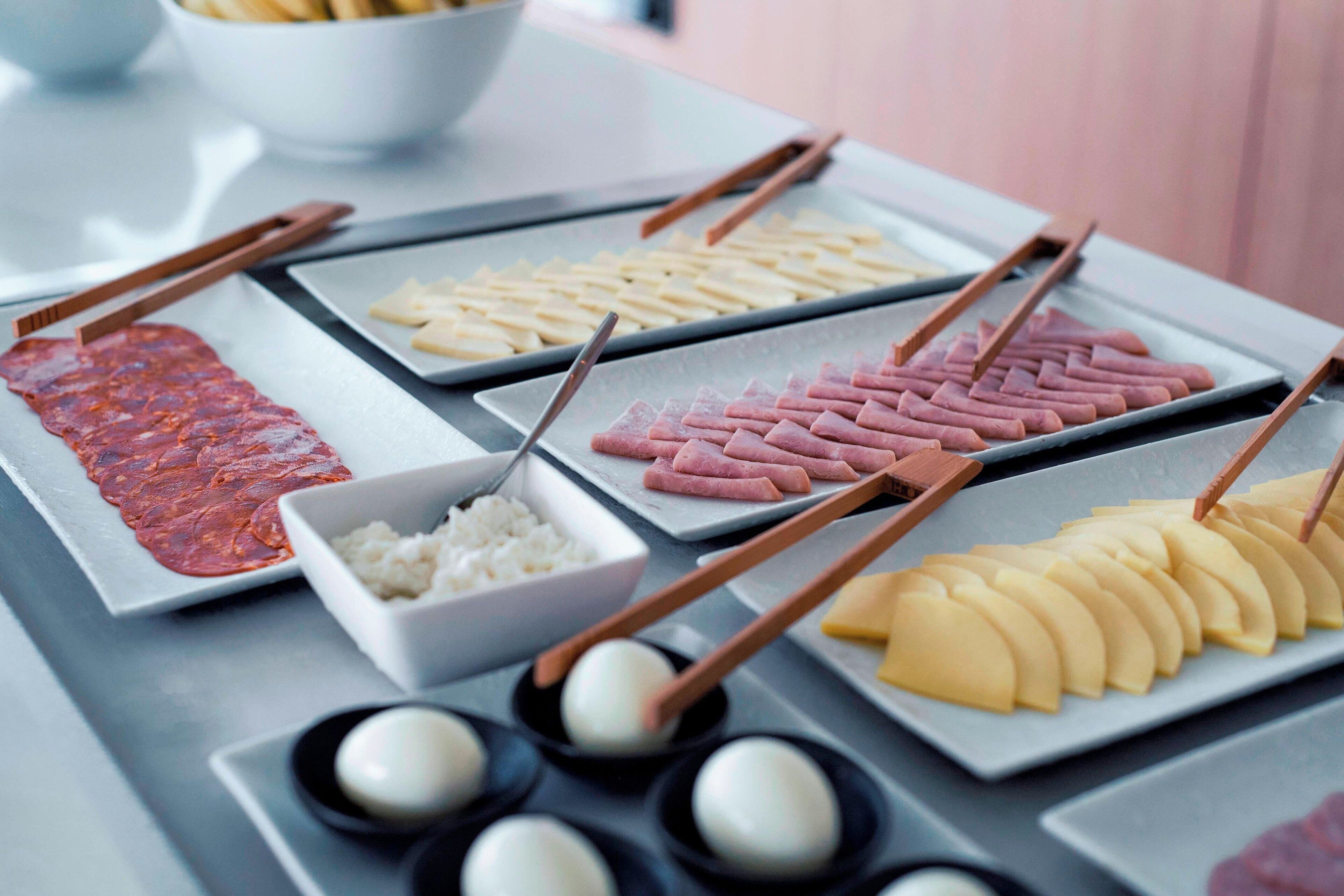 A table with various food items including sliced meat, pickled vegetables, and rice.