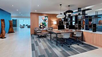A modern office space with a long table, several chairs, a large abstract painting, and a bookshelf.
