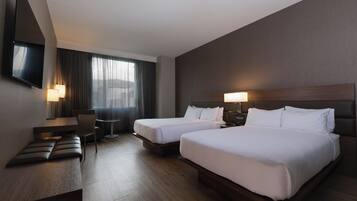 A hotel room with two beds, a desk, a chair, a TV, and a window with curtains.