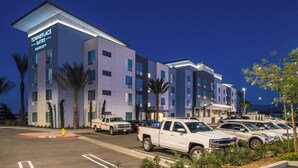A TownePlace Suites Marriott hotel with a parking lot, multiple vehicles, and palm trees.