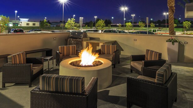 An outdoor seating area with wicker furniture and a central fire pit.