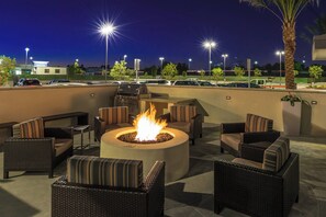 An outdoor seating area with wicker furniture and a central fire pit. - TownePlace Suites by Marriott Ontario Chino Hills (Chino Hills)