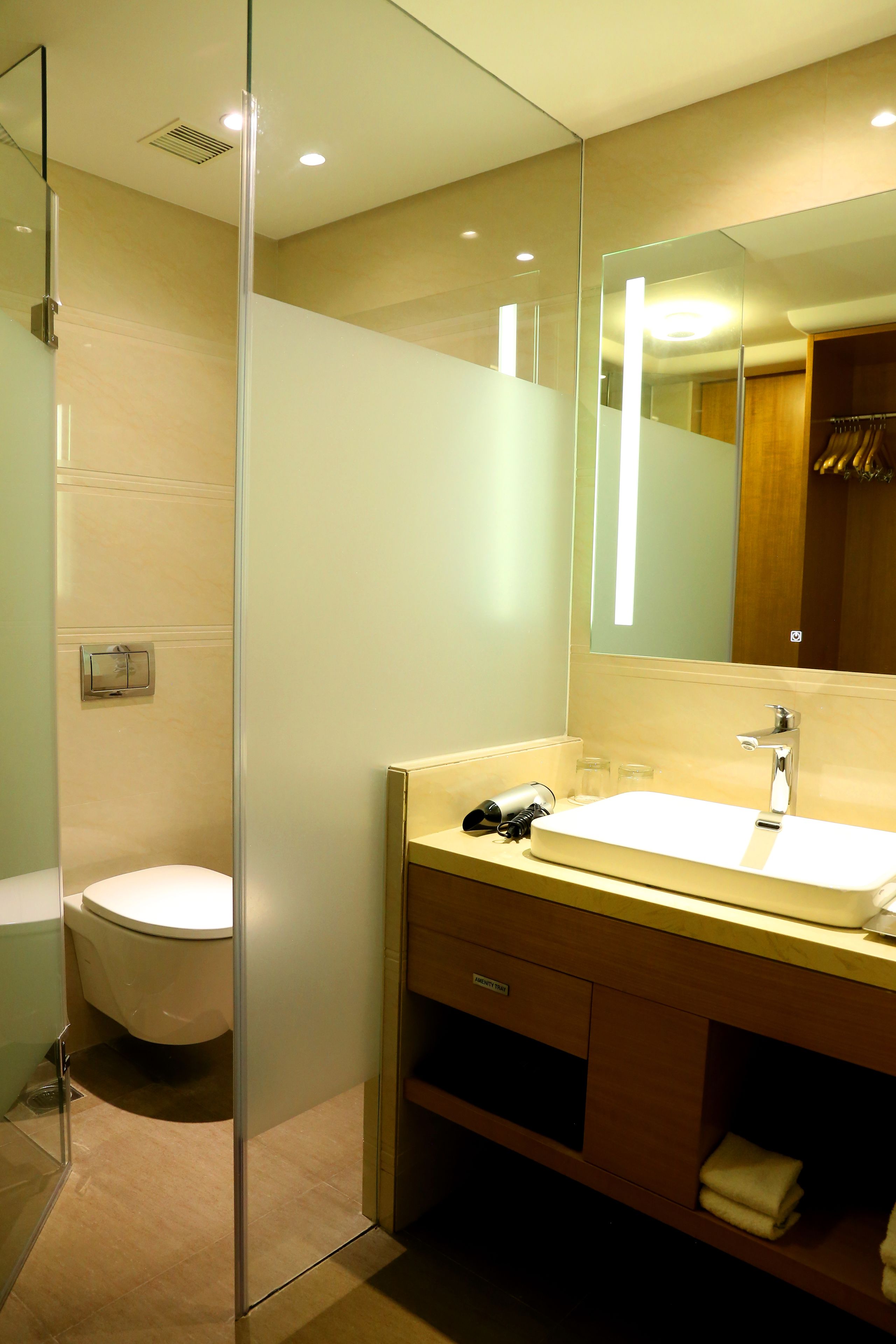 Un baño moderno con cabina de ducha de vidrio, un lavabo blanco y un espejo grande.