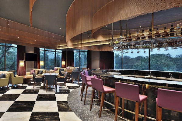 A modern bar area with a checkered floor, bar stools, and a wine display. - Courtyard by Marriott Madurai (Madurai)