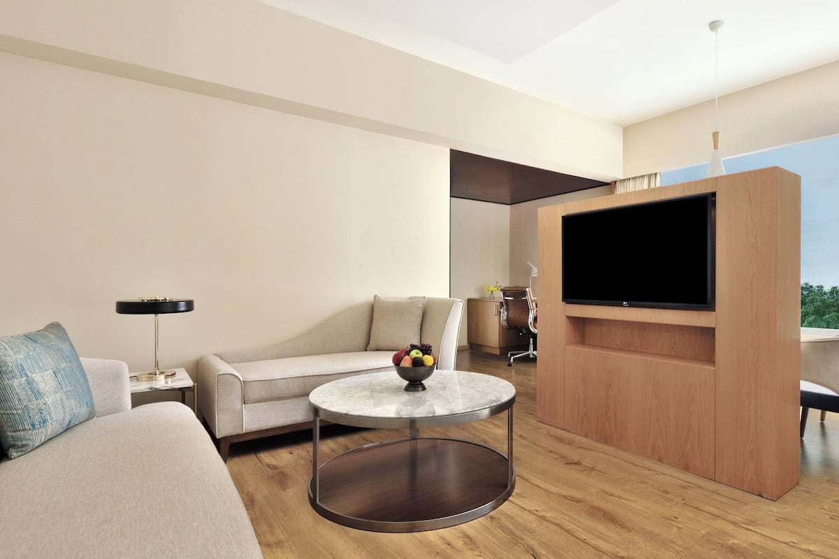 Ein modernes Wohnzimmer mit einem runden Marmortisch, einer Couch, einem Fernseher und einer Holz-Unterhaltungsanlage.
