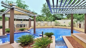 A swimming pool with a pergola and seating area, surrounded by plants and a tiled deck. - Courtyard by Marriott Madurai (Madurai)