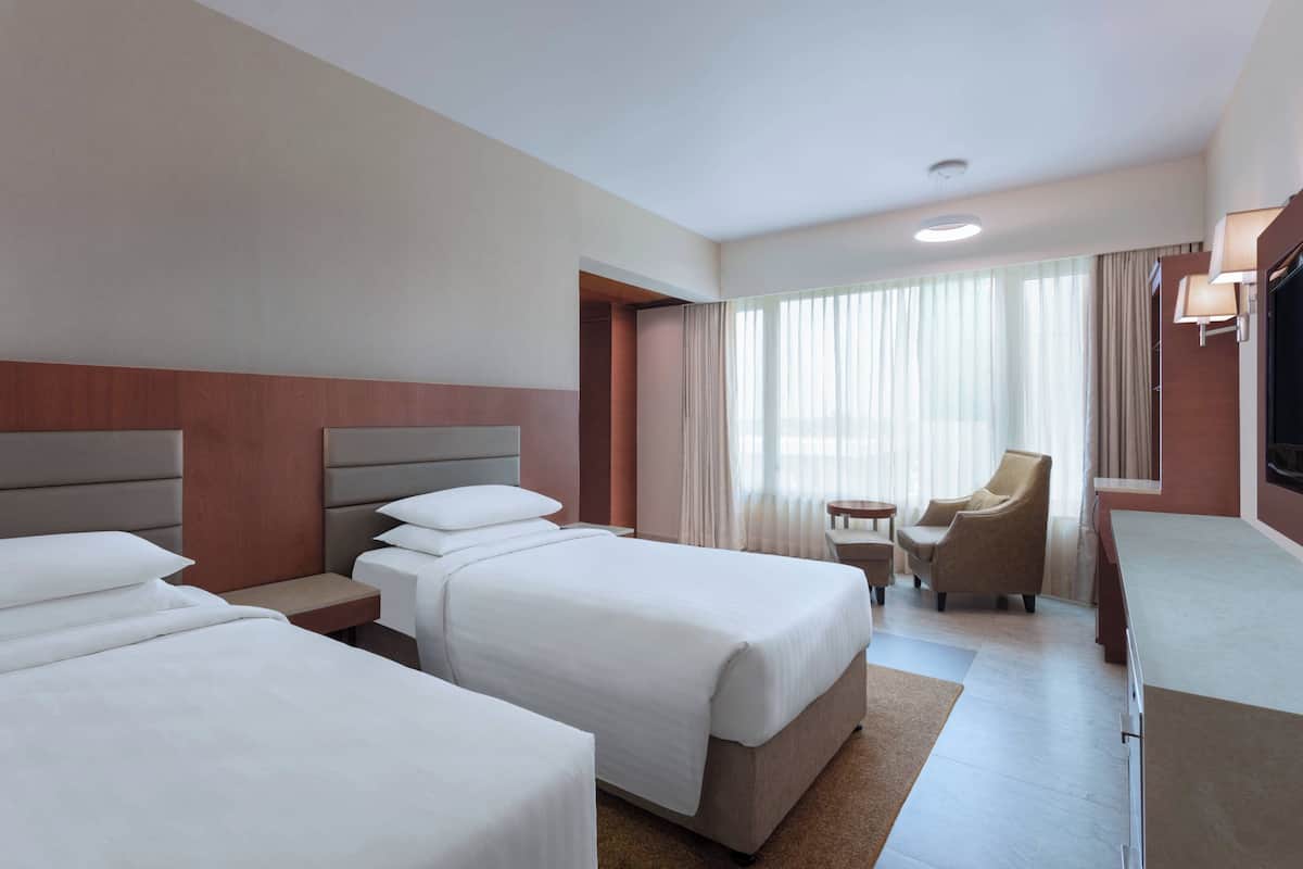 Ein Hotelzimmer mit zwei Betten, einem Schreibtisch, einem Stuhl und einem Fernseher.
